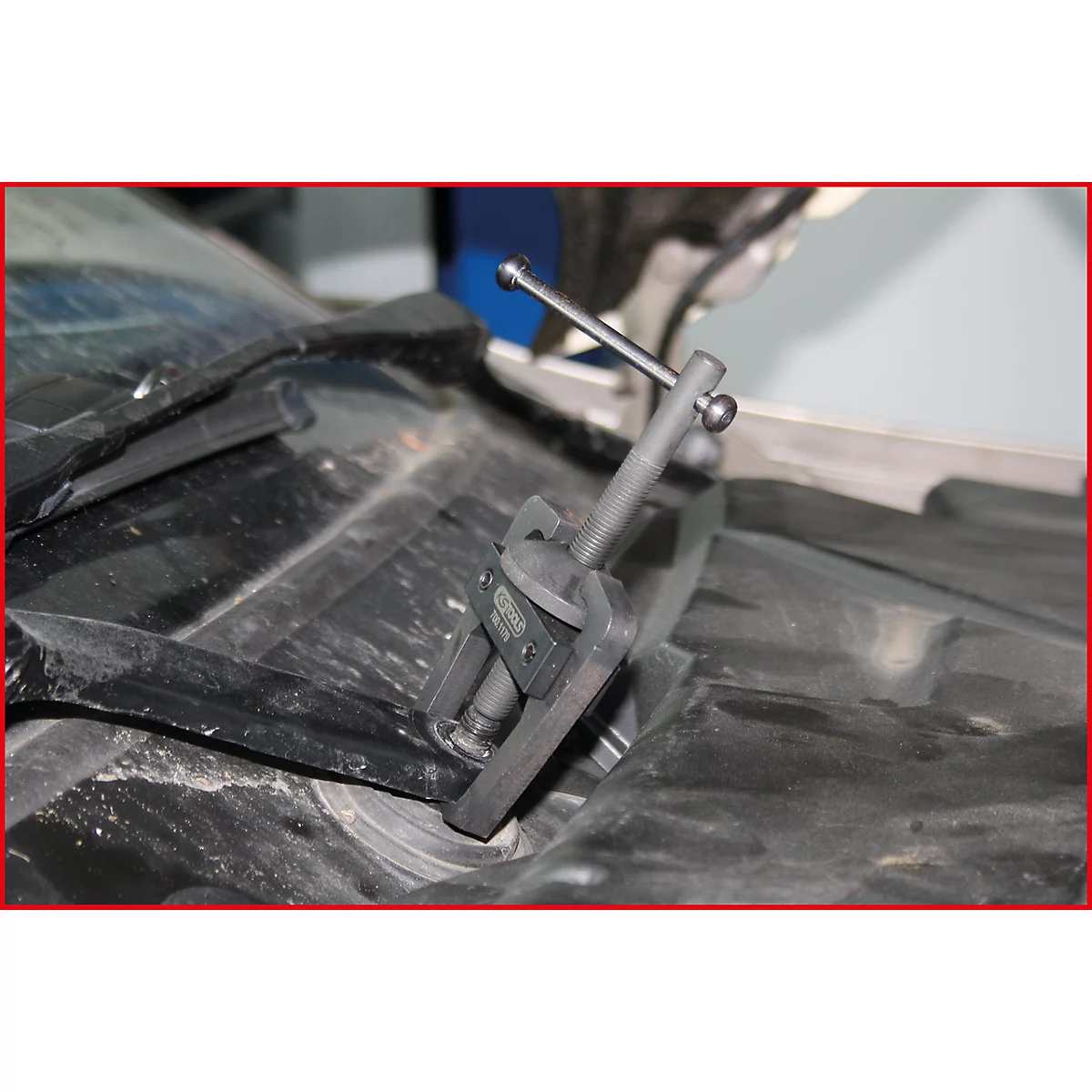 Werkzeug in einem Motorraum. Dunkelgraues Werkzeug, vermutlich zum Ausbau von Teilen, im Einsatz.